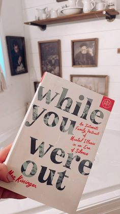 a person holding up a book with writing on it in front of a bathroom sink