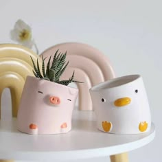 three ceramic pig planters sitting on top of a table next to plates and flowers