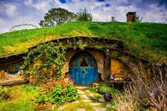 a hobbot house with a blue door surrounded by greenery