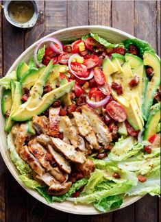 a salad with chicken, lettuce, tomatoes and avocado