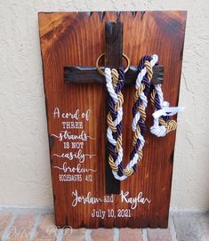 a cross made out of wood with two ropes attached to it and an inscription on the front