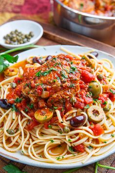 a plate of spaghetti with olives and tomatoes