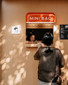 a woman standing in front of a mini bar with a sign on the wall behind her