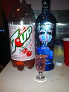 two bottles and a glass on a counter with ice cream, candy canes, and soda