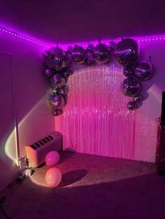 a room with balloons and disco balls on the wall, in front of a purple curtain