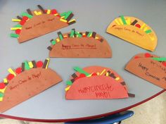 turkey hats with happy thanksgiving written on them sitting on a blue table in front of a blackboard