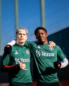 two soccer players are posing for the camera with their arms around each other while wearing green jerseys