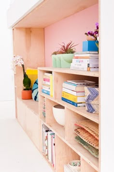 a book shelf filled with lots of books next to a vase and potted plant