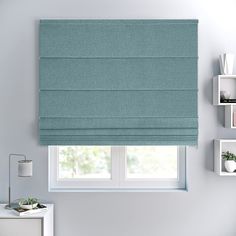 a blue roman blind in a bedroom with white walls and shelves on either side of the window