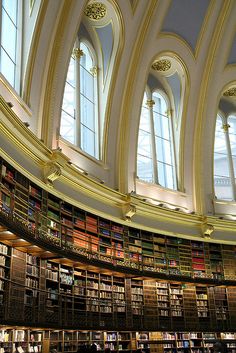 the inside of a large library with many bookshelves and arched ceiling lights on either side