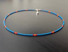 This necklace is made with Czech glass seed beads size 11/0in a mid tone, blue colour. Accent colours in red and yellow. The necklace comes with a 1 inch silver extender chain. Blue Choker With Tiny Round Beads, Blue Choker With Tiny Beads, Blue Single Strand Choker With Round Beads, Seed Bead Color Combinations, Blue Seed Bead Necklace, Hip Jewelry, Mens Beaded Necklaces, Red Beaded Necklaces, Beaded Necklace Patterns