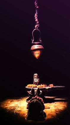 a lamp hanging from the ceiling in front of a dark room with lights on it