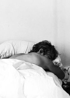 black and white photograph of a woman sleeping in bed with her head on the pillow