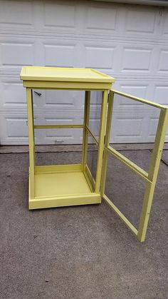 a yellow shelf sitting on the ground next to a white garage door with a window