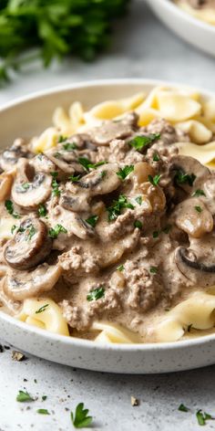 a white plate topped with pasta covered in mushroom gravy and garnished with parsley