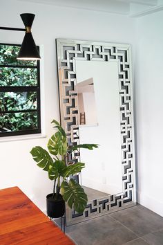 a mirror sitting on top of a wooden table next to a potted green plant