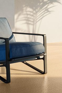 a blue chair sitting on top of a hard wood floor next to a white wall