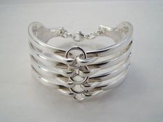 a stack of silver bracelets sitting on top of a white table