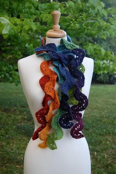 a white mannequin with multicolored scarves on it's neck