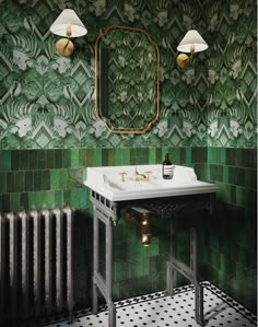 a bathroom with green tiles and gold fixtures on the wall, along with a white sink