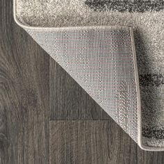 an area rug is shown on the floor with wood grained floors and grey carpeting