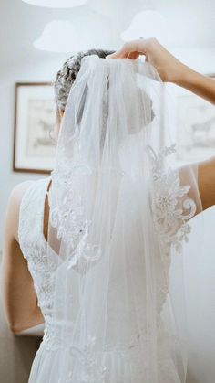 the back of a bride's wedding dress, with her veil draped over her head