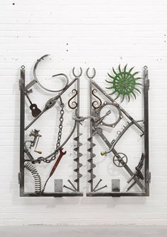 a metal sculpture with various tools attached to it's sides and hanging on the wall