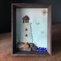 a wooden frame with rocks and pebbles in the shape of a lighthouse on top of it