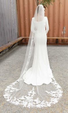 the back of a bride's wedding dress, with her veil blowing in the wind