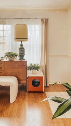 a living room filled with furniture and a lamp on top of a wooden table next to a window