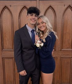 a young man and woman posing for a photo in front of a wooden wall with arched doorways