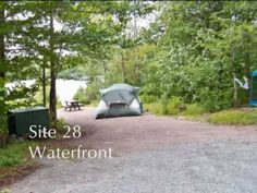 there is a tent set up in the woods next to a picnic table and bench