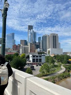 a person is standing on a bridge looking at the cityscape and river below