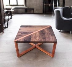 a wooden table sitting on top of a white floor next to a gray couch and two chairs