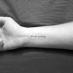 a woman's arm with the words keep going tattooed on her left forearm and wrist