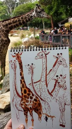 a person holding up a drawing of giraffes in front of a group of people