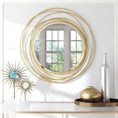 a white table with a mirror and vase on it next to a wall mounted sunburst