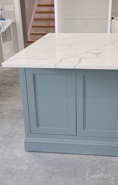 a kitchen island with marble top and blue cabinets