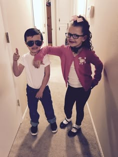 two young children standing next to each other on the floor in front of a door