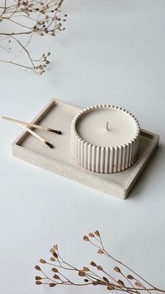 a white candle sitting on top of a wooden tray