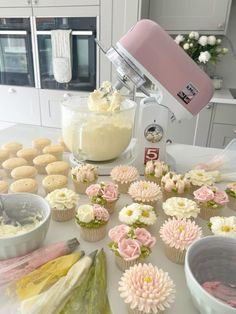 cupcakes are being made in a kitchen with flowers on the counter top and behind them is a mixer