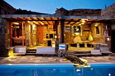 an outdoor living area next to a swimming pool at night with lights on the patio