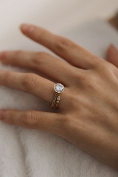 a woman's hand with a diamond ring on top of her left hand,