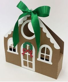 a paper house with a green ribbon tied around the top and two windows on each side