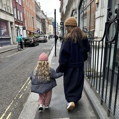 a woman and child are walking down the sidewalk