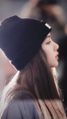 a woman with long hair wearing a black beanie and looking off to the side