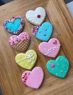 decorated heart shaped cookies sitting on top of a wooden table