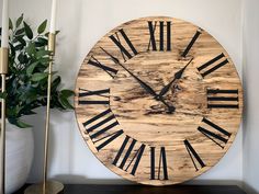 a large wooden clock sitting on top of a table next to a potted plant