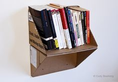 there is a cardboard box that has books in it on top of the book shelf