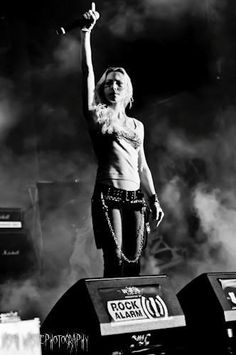 a woman standing on top of a stage with her arms in the air and hands up